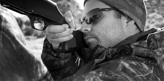 black and white closeup of man shooting a gun